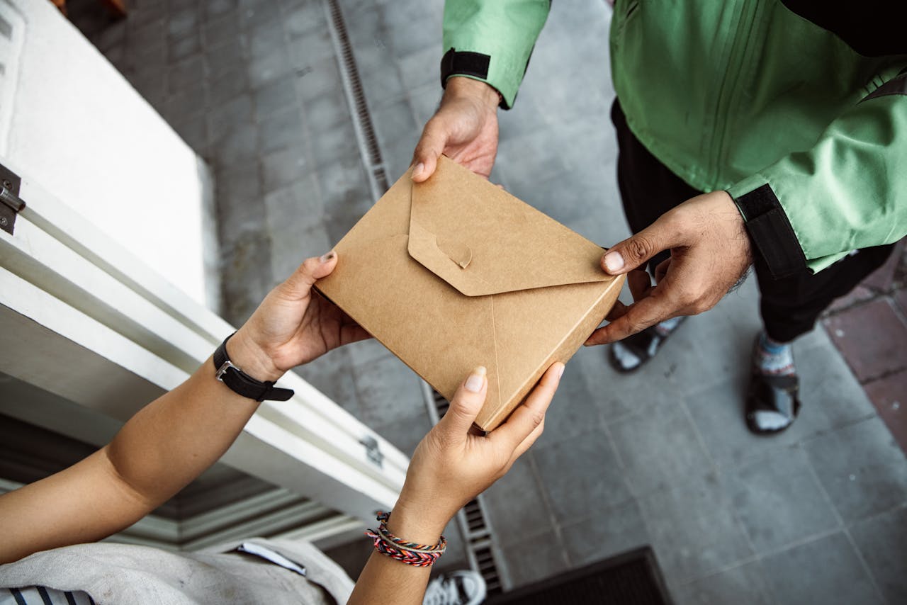services-01 A delivery person hands over a package to a customer outdoors, showing modern service interaction.