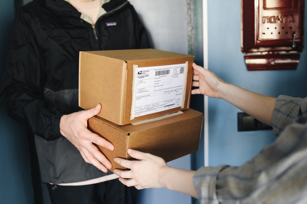 services-03 Close-up of hands exchanging cardboard boxes indoors, symbolizing delivery service.