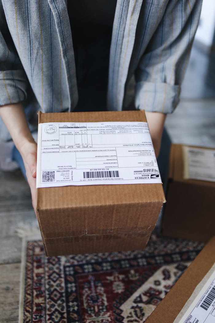 portfolio-02 Close-up of a person holding a cardboard box with shipping labels, ideal for delivery logistics visuals.