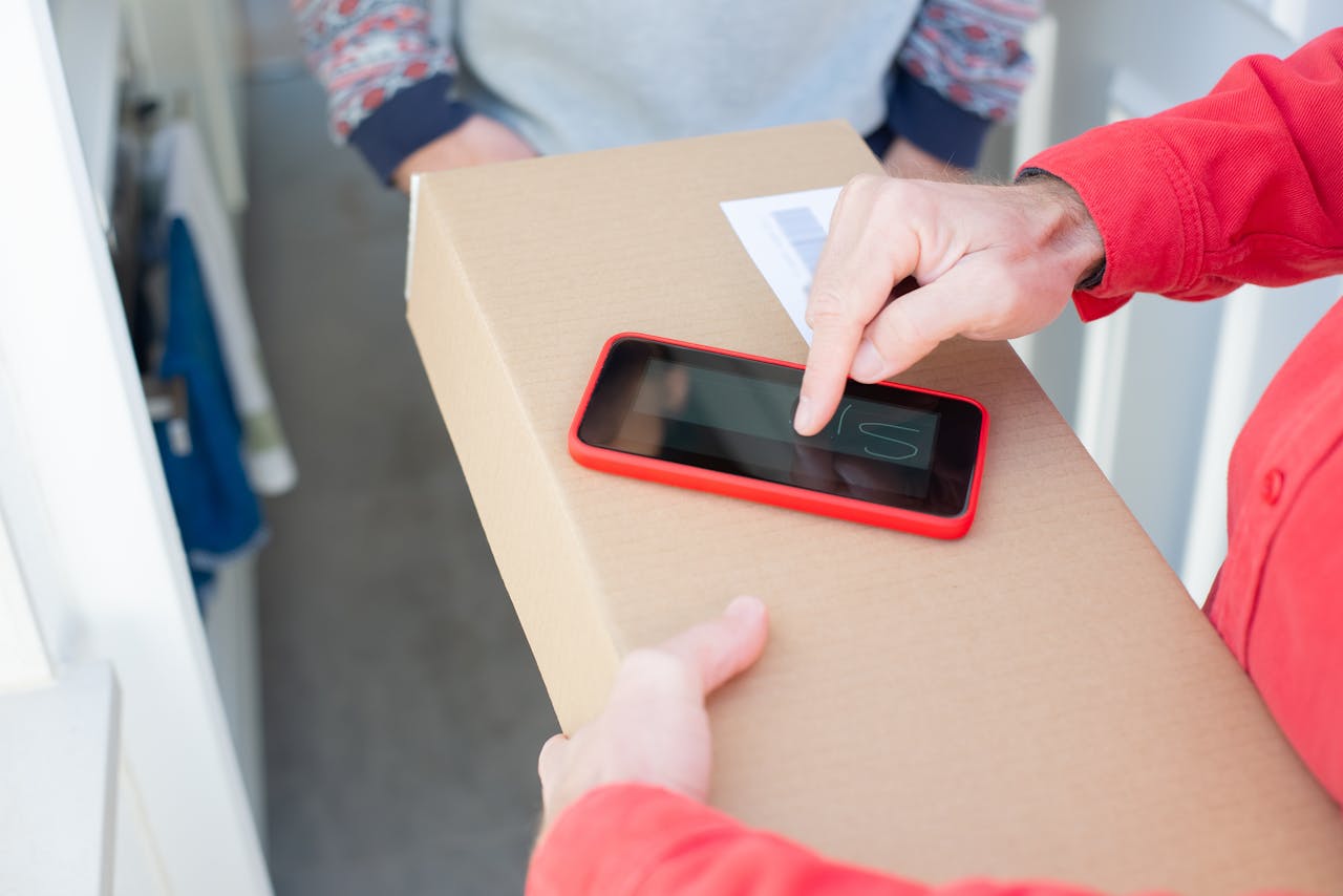 gallery-03 A person signs a package delivery confirmation using a smartphone, showcasing contact-free delivery.